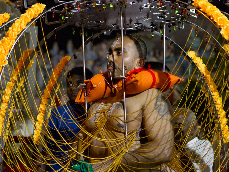 Участники шествия во время фестиваля Тайпусам несут на себе оригинально украшенные конструкции